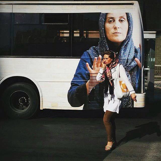 A woman passes by a public bus